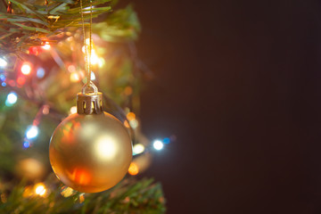 Christmas decoration. Hanging gold balls on pine branches christmas tree garland and ornaments over abstract bokeh background with copy space.