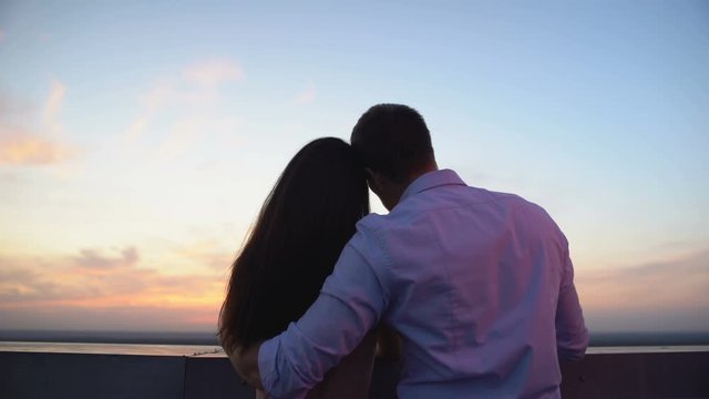 Male tourist hugging girlfriend and showing landmarks from observation deck