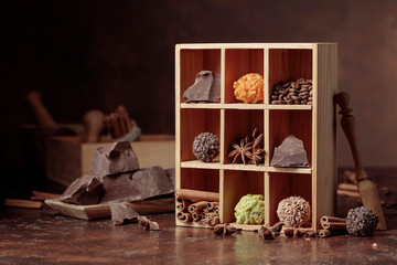 Chocolate truffles with broken pieces of chocolate and spices in wooden box.