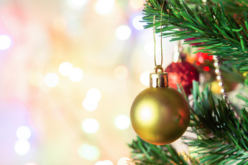 Christmas decoration. Hanging gold balls on pine branches Christmas tree garland and ornaments over abstract bokeh background with copy space.