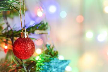 Christmas decoration. Hanging red glitter balls on pine branches Christmas tree garland and ornaments over abstract bokeh background with copy space.