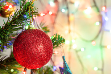 Christmas decoration. Hanging red glitter balls on pine branches Christmas tree garland and ornaments over abstract bokeh background with copy space.
