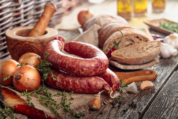 Dry-cured sausage with bread and spices on a old wooden table.