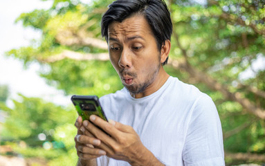 Young asian man shocked when he looking smartphone