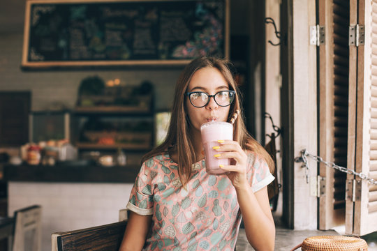 Teen girl drinking smoothie in cafe