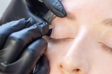 Woman using tweezers on patient eyebrow at the health spa. eyebrow shaping