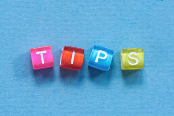 Tips inscription made of colorful small cubes on blue background.