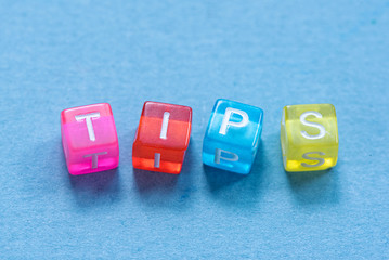 Tips inscription made of colorful small cubes on blue background.