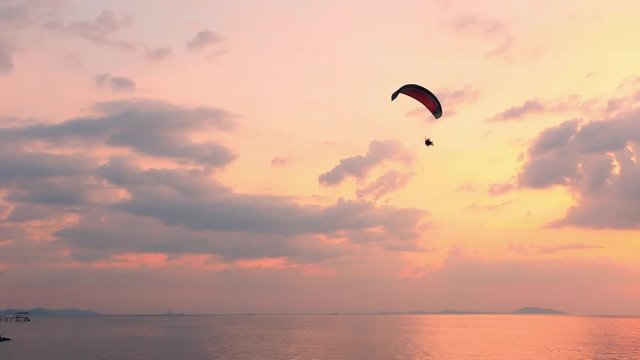 Guy flying on the clearly blue sky and wonderful beach by paramotor red kite,extreme activity port. feel freedom like birds. concept overcome the limits of  human physiology.