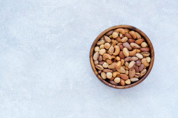 Roasted salted mixed nuts in wooden bowl. Top view with space for text