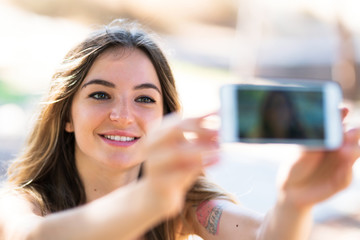 Young girl at outdoors taking a selfie with the mobile