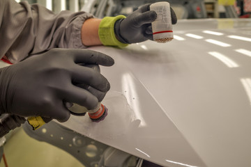 A worker in the painting shop of a car body, sanding painted items
