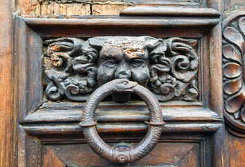 Close-up of an old wood carved door with a rusty metal knocker, Tuscany, Italy
