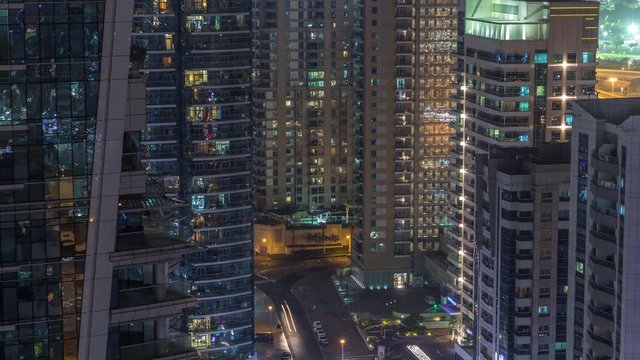 View of various skyscrapers and towers in Dubai Marina from above aerial night timelapse. Illuminated modern buildings in urban skyline with traffic on streets