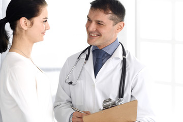 Doctor and patient discussing medical exam resoults at hospital office. Physician using clipboard for filling up medication history records. Perfect medical service in clinic. Medicine and healthcare