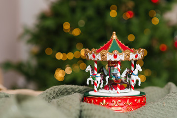 Christmas musical toy carousel on the background of the burning lights of the Christmas tree. Copying space © Sunshine