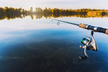 hand with spinning and reel on the summer lake
