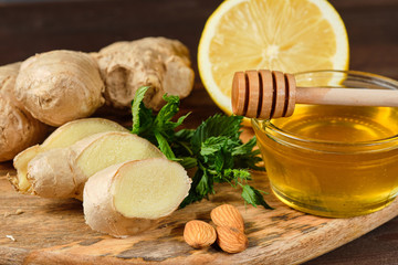 honey with ginger, lemon and mint and nuts on wooden Board and grey background. Close up