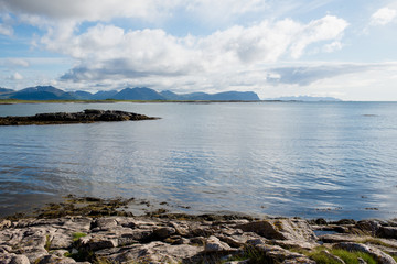 Beautiful nature landscape in North. Scenic outdoors view. Ocean with waves and mountains. Big dark stones. Dramatic storm clouds. Extreme weather, rain and wind. Explore Norway, summer adventure