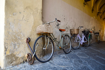 A row of bicycles parked under an old porch in the historic centre of Lucca, Tuscany, Italy