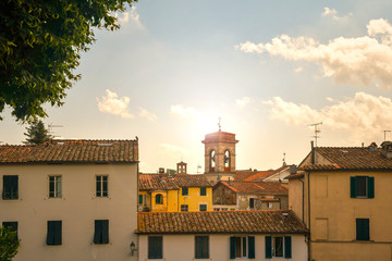 Backlight rooftop view of the medieval town of Lucca with the bell tower of the church of San...