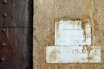 Stone wall with old marble plates reporting the water level data of 1767, with the engraving: "Cornerstone of levelling year 1767 -  19,65 meters above the sea level", Lucca, Tuscany, Italy