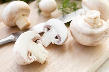 Sliced champignon mushrooms on wooden board   