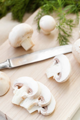 Sliced champignon mushrooms on wooden board   