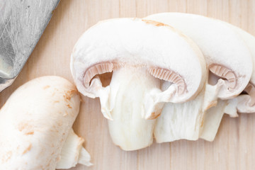 Sliced champignon mushrooms on wooden board   