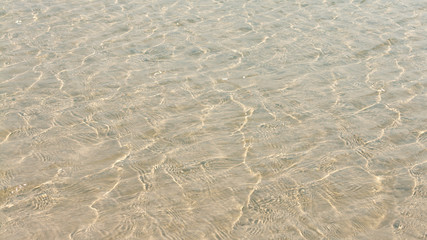 Fototapeta na wymiar Transparent water ripple, sand waves and sunlight glare. sea floor pattern
