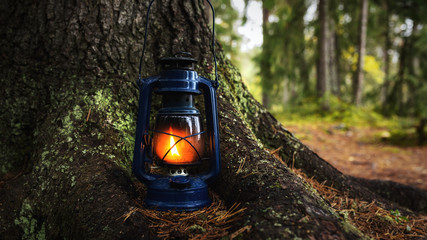 Burning old oil lamp in forest.  Selective focus.