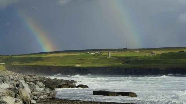 Irland mit dunklen Himmel und Regenbogen mit Gischt