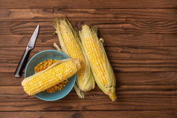 corn on woody table with knife and blue plate
