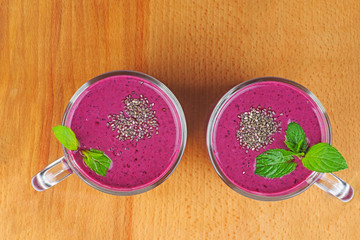 Glasses of homemade blueberries smoothie and fresh mint leaf on wooden background