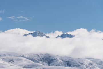 Fototapeta na wymiar Panoramic snow mountains over white clouds and blue sky