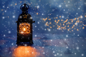 Lantern with candles on a beautiful blue background with gold dust, stars and snow. Beautiful...