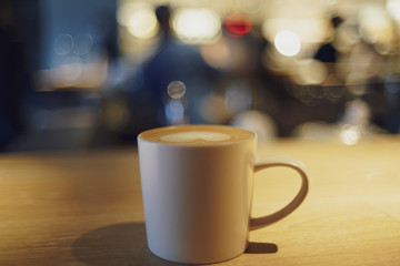 coffee latte art on wood table with bokeh light background- soft focus