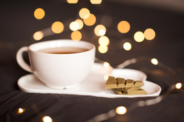 Cup of fresh green tea and matcha chocolate over lights at bakground closeup. Good morning. Breakfast. Detox.