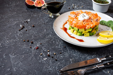 Delicious avocado and salted salmon tartar on black stone background