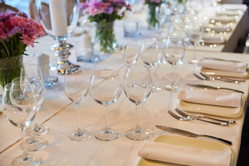 Table setting for guests in a restaurant, on the table forks and glasses for wine - flowers in a vase and a candle on the table