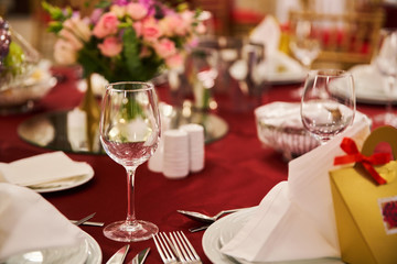 Table setting for guests in a restaurant, on the table forks and glasses for wine - flowers in a vase and a candle on the table