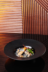 black spaghetti pasta with cuttlefish ink, mussels and red caviar in a beautiful black plate on a dark texture background. close-up. space