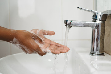 closeup of a boy scrubbing soapy hand against washbasin. Concept of a hand hygiene and global...