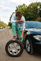 Car breakdown, young man puts the spare tyre