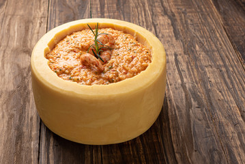 Italian shrimp risotto served inside a big Parmesan Cheese Wheel on a wooden background