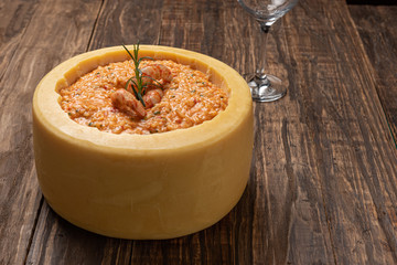 Italian shrimp risotto served inside a big Parmesan Cheese Wheel on a wooden background