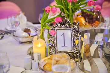 Table setting for guests in a restaurant, on the table forks and glasses for wine - flowers in a vase and a candle on the table