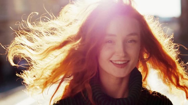 Glamorous cute ginger young woman with positive mood walking confident on street in city center. Female irish beauty.
