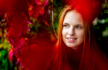 portrait of young teenager redhead girl with long hair on autumn plant leaves background