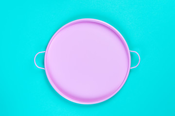 Pink tin circle tray on blue paper background, top view with copy space for your design, frame. Still life composition.